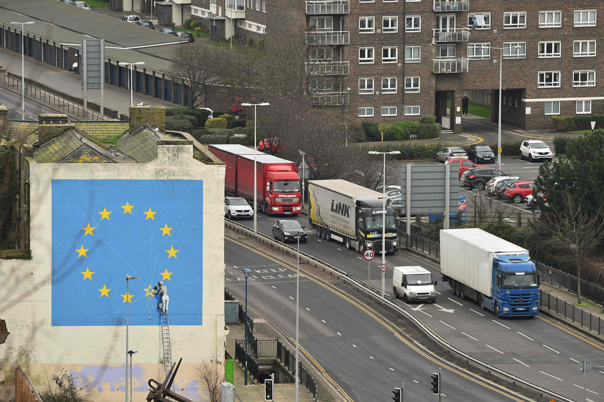 Een muurschildering van de Britse artiest Banksy en een groepje vrachtwagens in Dover.  Beeld AFP