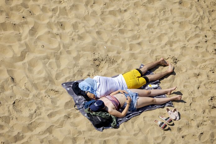 Zonaanbidders op het strand van Scheveningen genieten tijdens een warme lentedag.