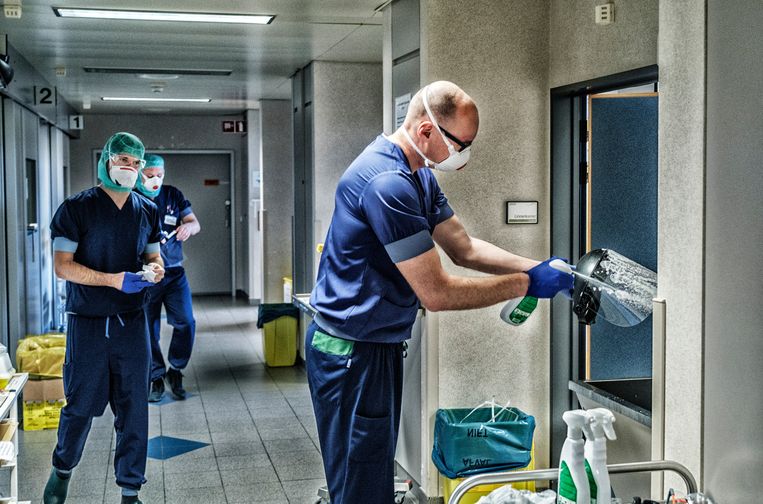 Intensivist Michiel Van Tornout spoelt zijn spathelm af na een consultatie in de besmette zone. Beeld Tim Dirven