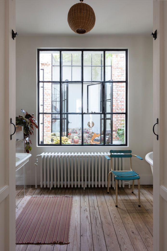 De badkamer is artisanaal afgewerkt met een houten vloer, ijzeren ramen en een gietijzeren verwarming.