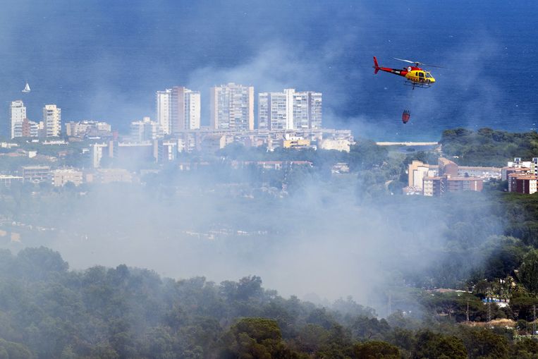 Een helikopter blust een bosbrand die is ontstaan in Santa Cristina d'Aro, Girona, Spanje. In totaal zijn er 74 korpsen van de regionale brandweer, waaronder 14 vanuit de lucht, in het gebied ingezet. De brand rond de stad in het Noorden van Spanje heeft al 35 hectare in de as gelegd. Beeld ANP / EPA