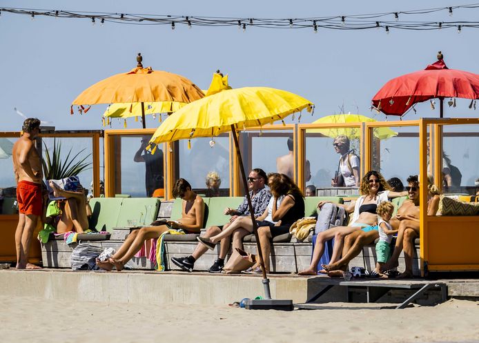 Strandgangers zoeken verkoeling op het strand bij Wijk aan Zee.