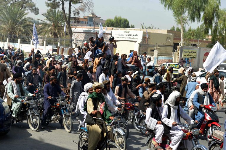 Afghanen die de Taliban steunen zwaaien met vlaggen van de beweging in Kandahar om het vertrek van de Amerikanen te vieren. Beeld AFP