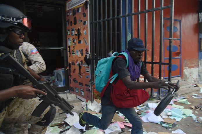 De Haïtiaanse politie probeert een man te arresteren die een winkel plunderde in de hoofdstad Port-au-Prince tijdens rellen tegen president Jovenel Moise.