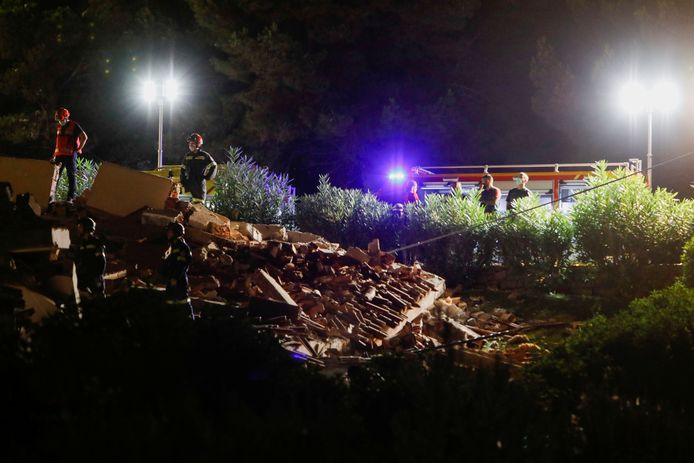Brandweerlieden bij de resten van het ingestorte gebouw.