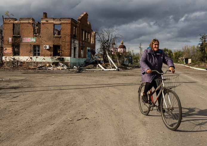 Een Oekraïense vrouw rijdt op haar fiets door de verwoeste straten van Drobysheve, een van de dorpjes in de buurt van Lyman, in de regio Cherson die recent door het Oekraïense leger werden bevrijd.