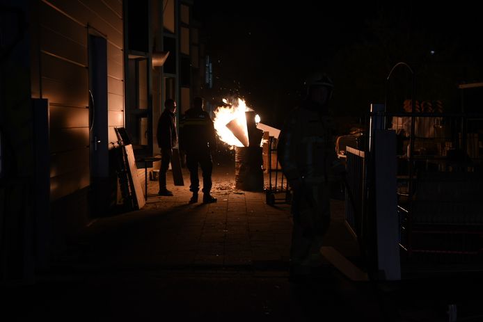 Een ton met laminaatplanken staat in brand.