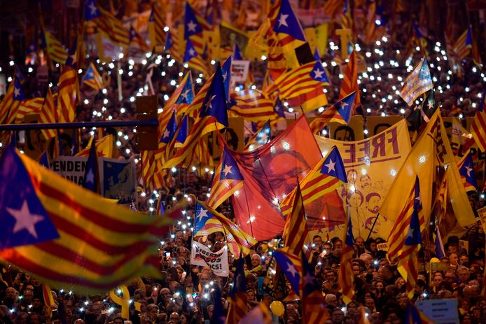 Mensen houden onafhankelijkheidsvlaggen en portretten van de gevangen politici omhoog in Catalonië tijdens een pro-onafhankelijkheidsdemonstratie.