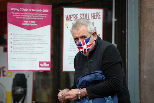 Een man met een mondmasker in Portsmouth, Engeland. Bijna 950.000 mensen zijn deze maand in Groot-Brittannië voor de eerste keer ingeënt.