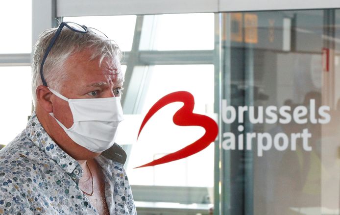 Een reiziger met mondmasker bij aankomst op Brussels Airport maandagochtend.