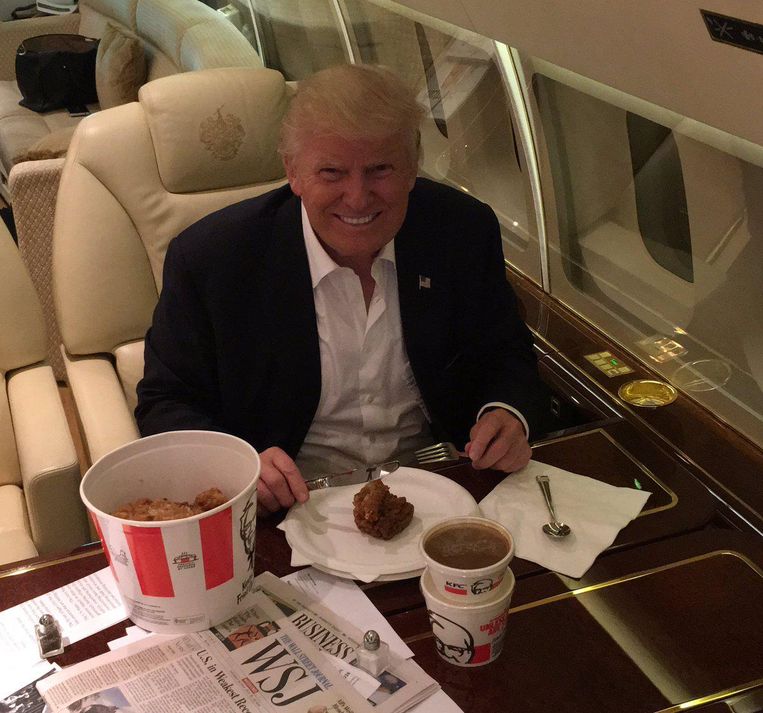 In de Trump Force One met een bucket van Kentucky Fried Chicken Beeld  