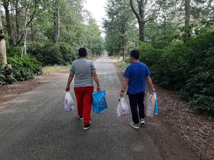 Twee Afghaanse evacués lopen met tassen vol etenswaar terug naar de noodopvang in Heumensoord.