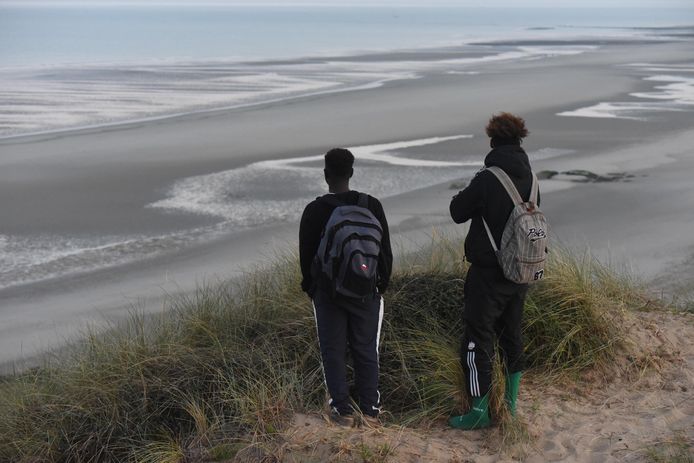 Migranten kijken vanaf de Franse kust uit over het Kanaal, dat ze illegaal met een bootje willen oversteken. Foto van september dit jaar.