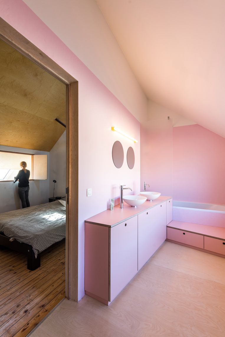 De slaapkamer onder het dak voelt als een kapel en kreeg zelfs luikjes.  En ernaast: een roze badkamer.    Beeld Luc Roymans