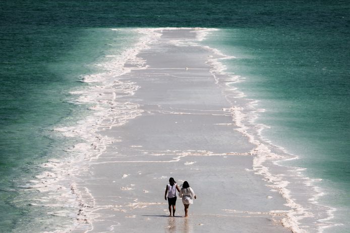 Toeristen wandelen op zoutformaties in de Dode Zee aan de Israëlische kust.