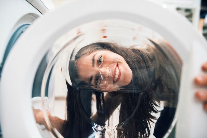 woman smiling cheerfully through a washing machine door