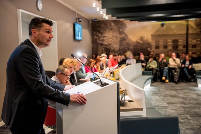 Ouder Martijn Loos voert het woord. Op de publieke tribune luisteren andere ouders toe.
