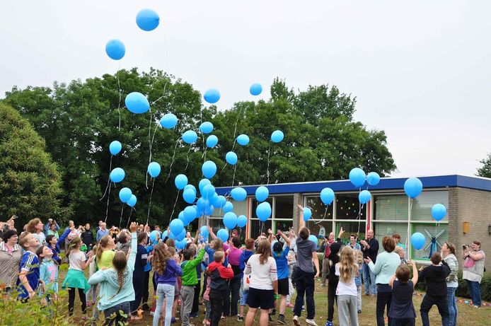 Voorzien van blauwe ballonnen laten de leerlingen de sleutel van de school de lucht in gaan