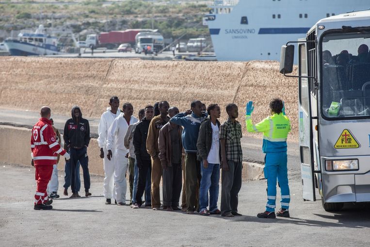 Bootvluchtelingen wachten voor de bus die hen naar een opvangcentrum zal brengen. Beeld Joost De Bock