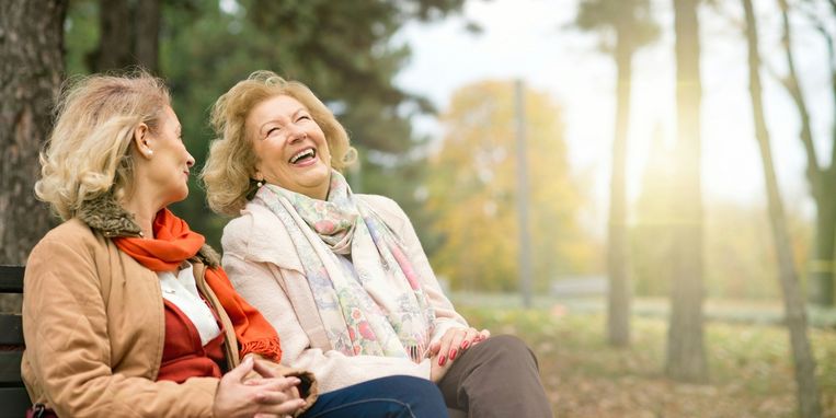 Two laughing senior friend relaxing at the park Beeld Getty Images