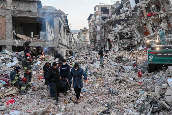 Mensen dragen een lijkzak terwijl lokale bewoners wachten tot hun familieleden uit het puin van ingestorte gebouwen worden gehaald in Hatay, Turkije.