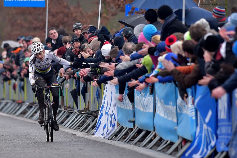 Van Aert deelt high fives uit aan het toegestroomde publiek vlak voor de finish. Beeld Belga