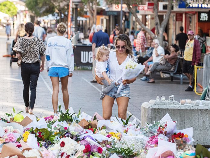 Een vrouw en een kind leggen bloemen neer bij het winkelcentrum waar het drama plaatsvond.
