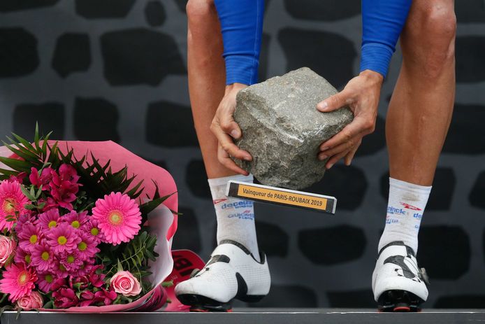 Winnaar Philippe Gilbert rapt de kassei op, de trofee die hoort bij de wielerklassieker Parijs Roubaix.