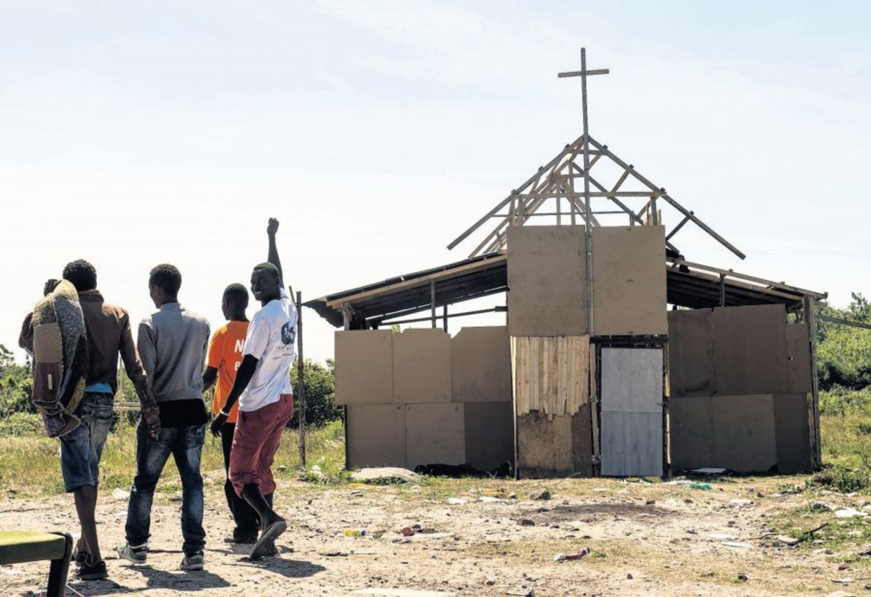 In het provisorische vluchtelingenkamp bij Calais hebben bewoners eigenhandig een kerk gebouwd. Daar kunnen ze een schiet- of ander gebedje doen voor ze een poging wagen om het Kanaal over te steken. Beeld afp