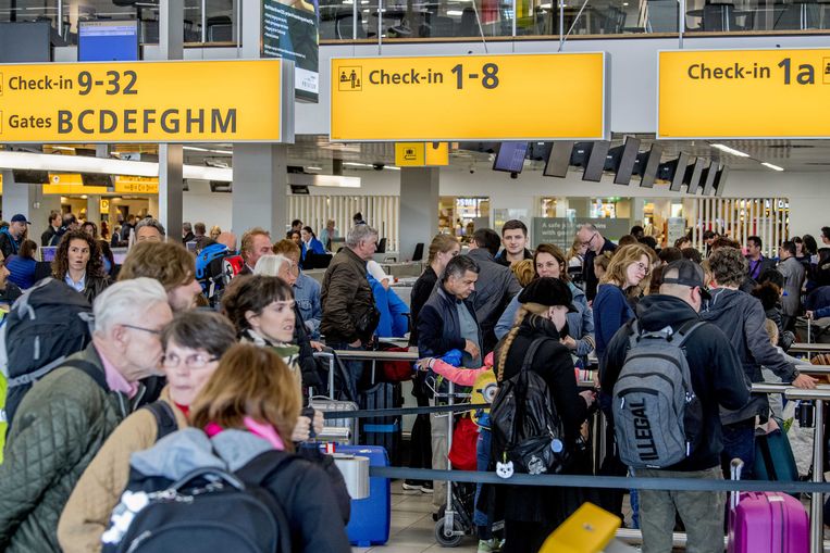 Reizigers wachten in rijen voor de check-ins en security check op luchthaven Schiphol. Beeld ANP