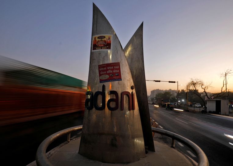 Verkeer rijdt langs het logo van de Adani Group op een rotonde op de ringweg in Ahmedabad. Beeld REUTERS