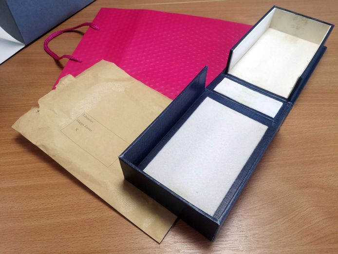 Het tasje, een van de twee doosjes en de getypte boodschap op een bruine envelop.