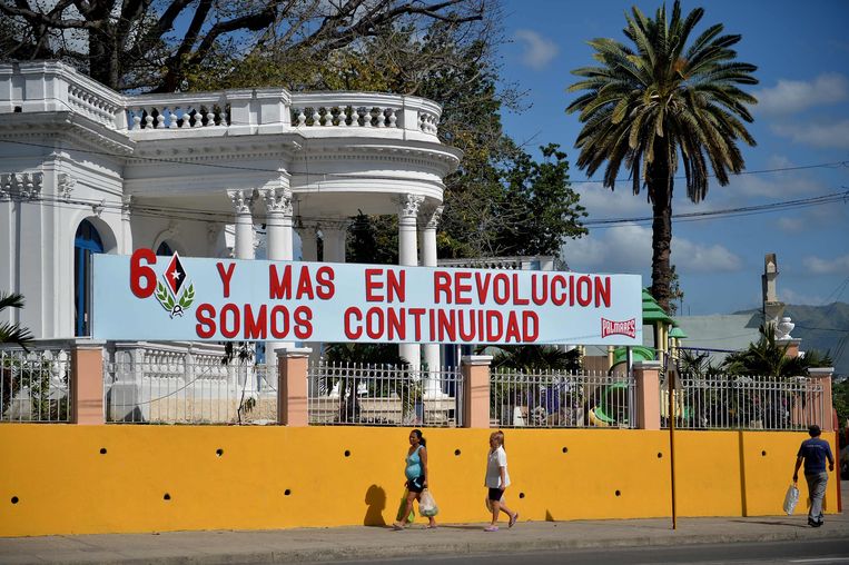Spandoek op straat in Santiago de Cuba. Vrij vertaald: ‘60 jaar revolutie en we gaan door’. Beeld AFP