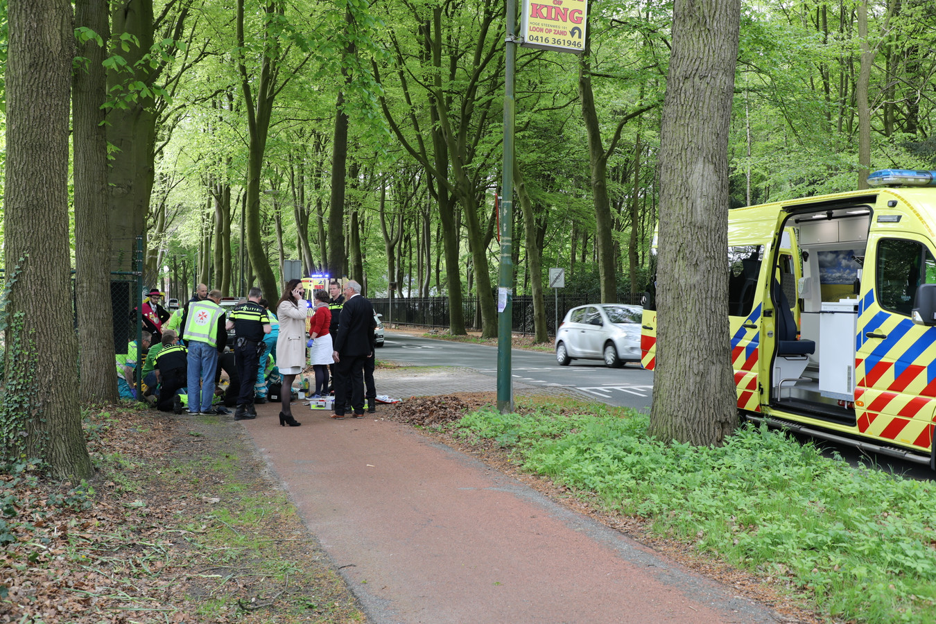 Burgemeester Hanne van Aart (in witte jas) belt terwijl ambulancemedewerkers zich over het slachtoffer ontfermen.