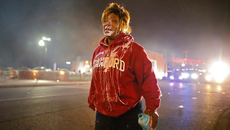 Een demonstrant in Ferguson heeft melk over haar gezicht gegoten nadat ze traangas in haar ogen had gekregen. Na het besluit van een jury om een blanke agent niet te vervolgen wegens het neerschieten van de zwarte tiener Michael Brown, afgelopen augustus, braken rellen uit. Er zijn gisteren honderden extra militairen van de Nationale Garde naar Ferguson gestuurd om escalatie te voorkomen. Beeld EPA