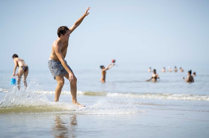 Een man vermaakt zich op het strand. Nu er een periode met zonnig en heet zomerweer is aangebroken, zijn mensen op zoek naar verkoeling.