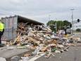 De container belandt op de zijkant en verliest lading bouwafval op de weg