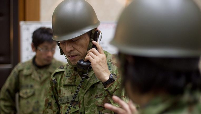 Een Japanse legerofficier overlegt met zijn collega's over de evacuatie van omwonenden in de buurt van de kerncentrale van Fukushima. Beeld epa