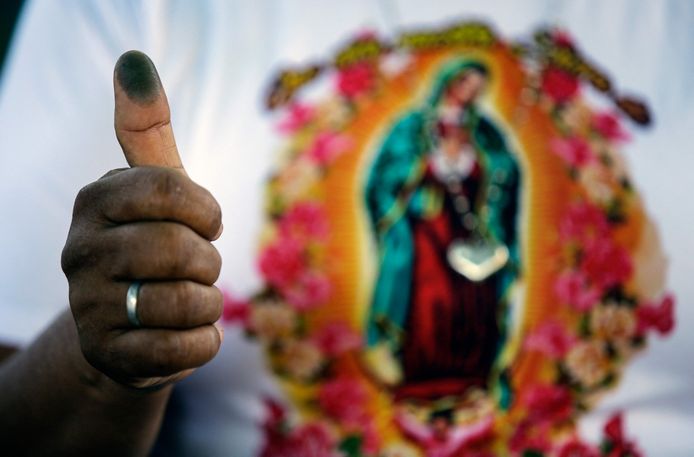 Een vrouw toont de inkt op haar duim als bewijs dat ze gestemd heeft.