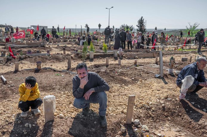 Een man en zijn zoon rouwen bij een graf op een begraafplaats in het Turkse Adiyaman. Beeld van 21 april.