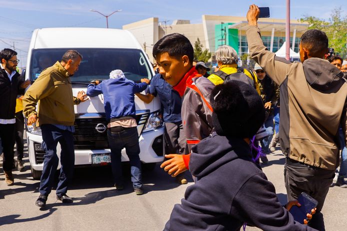 Migranten proberen de auto tegen te houden waarin de Mexicaanse president Andres Manuel Lopéz Obrador arriveert voor een bezoek aan het opvangcentrum in Ciudad Juárez.