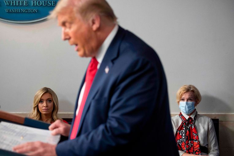 Dr. Deborah Birx (rechts, met mondmasker) en de woordvoerder van Trump luisteren eind juli naar een persconferentie van de Amerikaanse president.  Beeld AFP