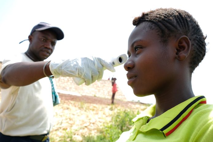 Een medewerker van het ministerie van Volksgezondheid van de Centraal Afrikaanse Republiek meet de temperatuur van een reiziger vanuit Congo. Reizigers worden gecontroleerd om te zorgen dat het ebolavirus niet verder verspreid.