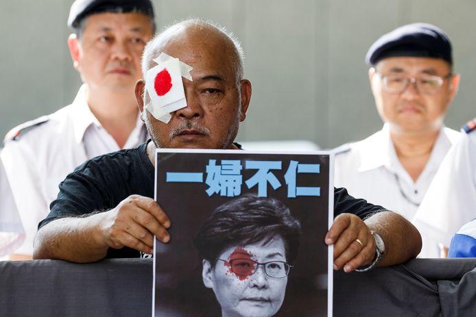 Een demonstrant houdt een foto van Carrie Lam omhoog, met een rode vlek op het oog. Die verwijst naar een demonstrante die door het harde optreden van de politie aan haar oog gewond raakte.