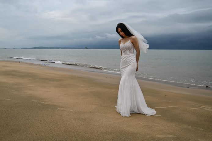 Une mariée pose, heureuse, sur une plage face à Taïwan.