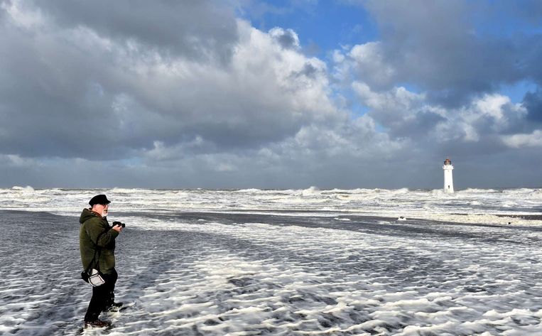 Een man maakt vandaag foto's van de zee op een strand nabij Liverpool tijdens de herfststorm. Beeld afp