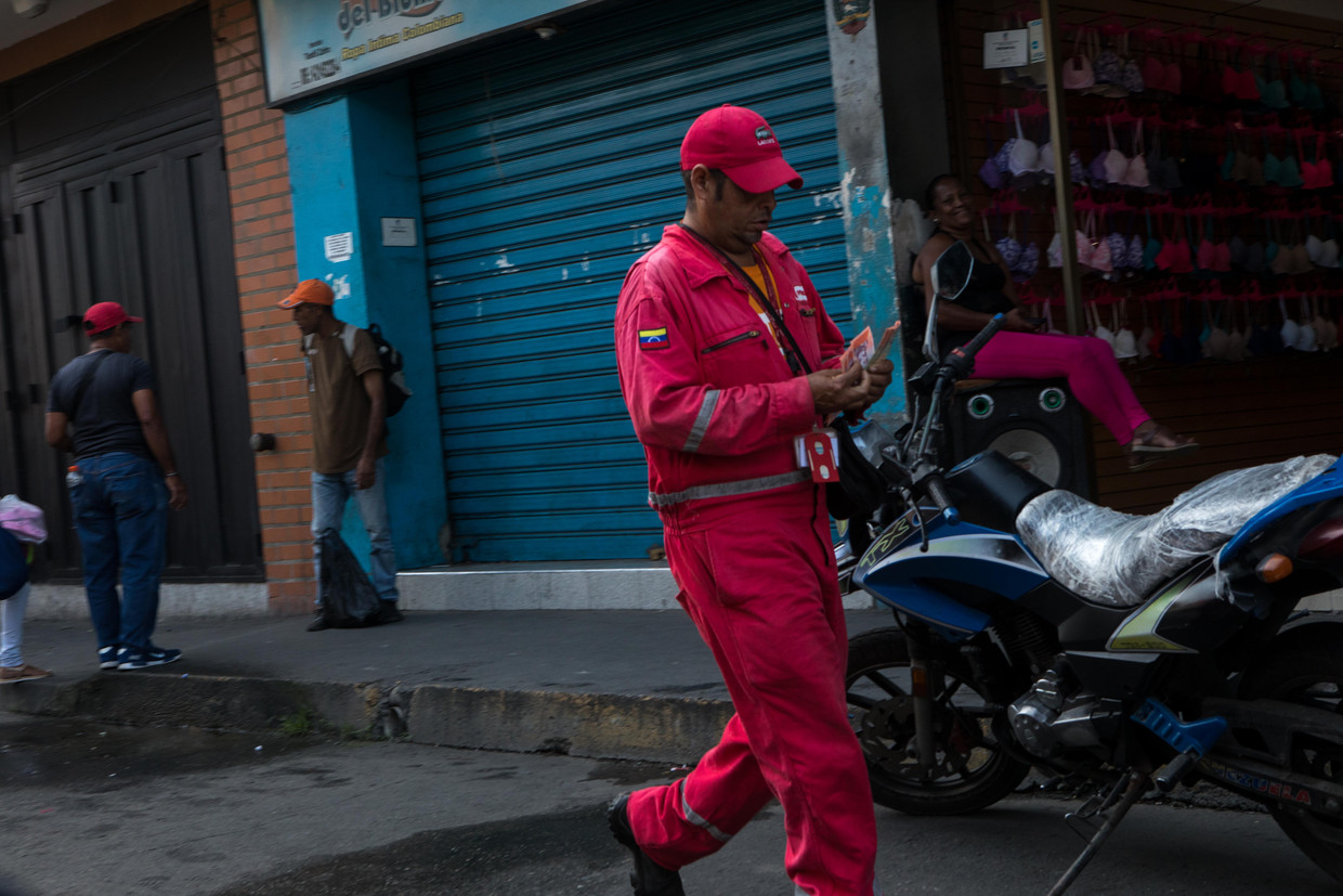 Een medewerker van een olieraffinaderij telt zijn geld in Puerto Cabello.  Beeld Cristian Hernandez