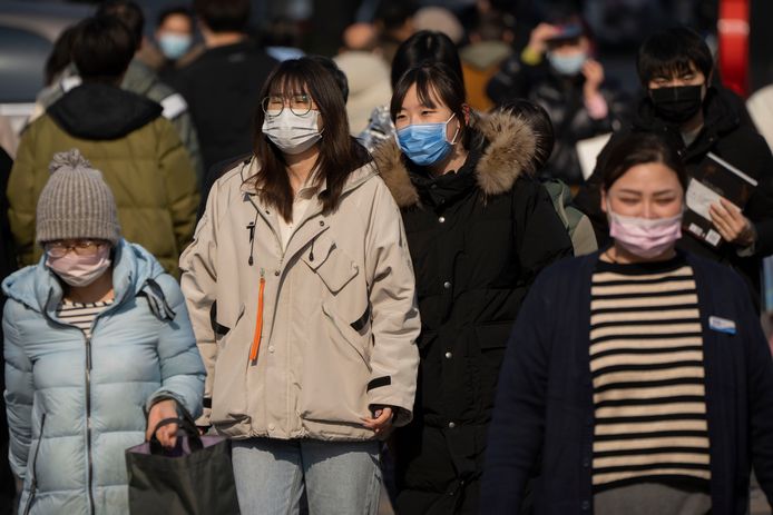 People wearing face masks walk across an intersection in Beijing, Tuesday, Feb. 7, 2023. (AP Photo/Mark Schiefelbein)