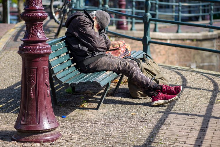 Een dakloze slaapt in de zon op een bankje aan de Amsterdamse Prinsengracht.  Beeld Hollandse Hoogte / Herman Wouters
