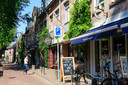 Bergstraat nieuwe stijl met vlaggen en geveltuinen en struiken. Gezien vanaf de Grote Berg.